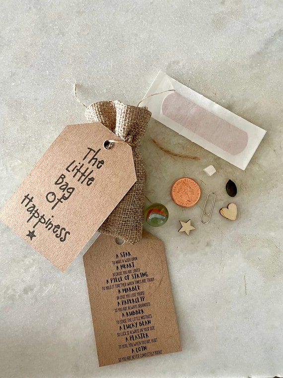 En liten tygpåse med texten 'The Little Bag of Happiness' och tillhörande småsaker.