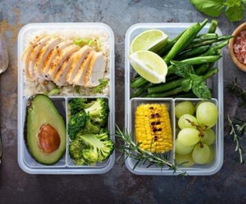 Två matlådor med kyckling, ris, grönsaker, frukt och lime